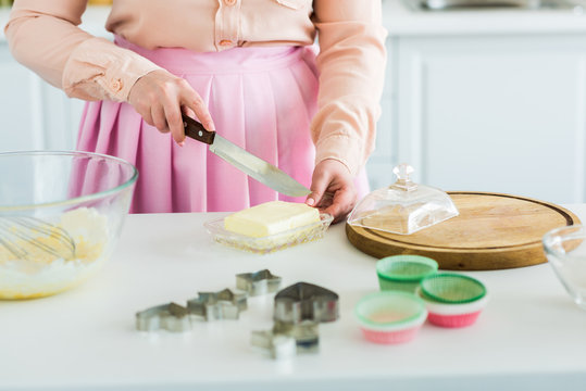 cropped image of woman cutting butter at kitchen