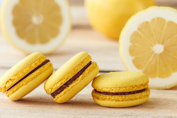Fototapeta na wymiar Yellow french macarons with lemons on the wooden boards