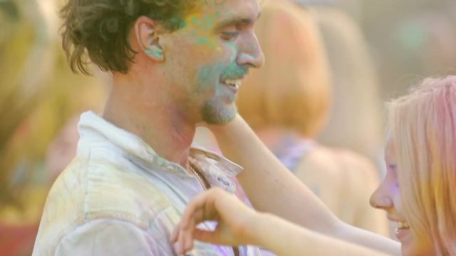 Happy couple colored in powder dancing, kissing and flirting at Hindu festival