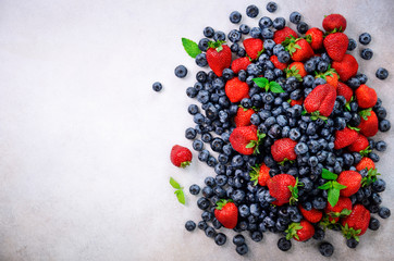 Summer berries background with copy space for your text. Top view. Food frame, border design. Mix assortment of strawberry, blueberry, currant, mint leaves. Vitamin, vegan, vegetarian concept.
