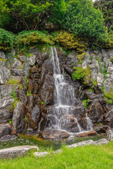 Fototapeta na wymiar Small waterfall in public city park.