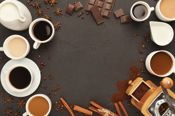 Top view on various coffee cups, scattered beans and spices, background with copy space