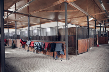 Horse barn with open wooden door. With set of saddle pads