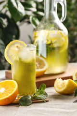 citrus mint lemonade with ice cubes in glass Cup next to vintage carafe. Summer drink Limoncello