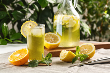 citrus mint lemonade with ice cubes in glass Cup next to vintage carafe. Summer drink Limoncello
