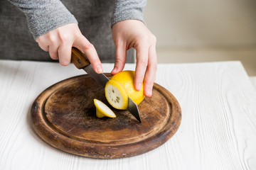 Woman cuts lemon into slices close