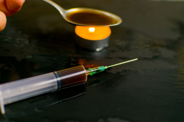 The concept of drug addiction. Background from the image of a syringe with a drug blurred in dark tones, preparation of a drug.