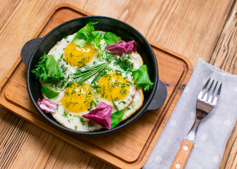 fried eggs in a frying pan and greens.
