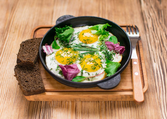 fried eggs in a frying pan and greens.