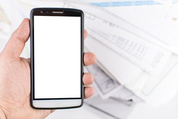 A man's hand holds a mobile phone against a background of scattered documents. mock-up.