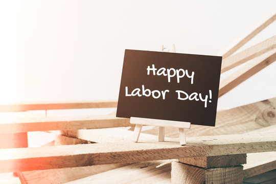 Small chalk board with text Happy Labor Day with wooden pallet background on white background with filter effect. International Workers' Day