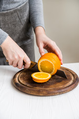 Woman cuts orange on board close