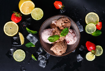 Portion of ice cream scoops with fruit on black