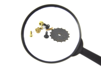 Screws and gear under magnifying glass on white background closeup