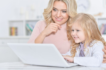 young woman and little girl using laptop