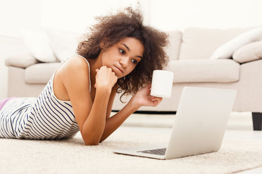 Serious girl with laptop lying on floor