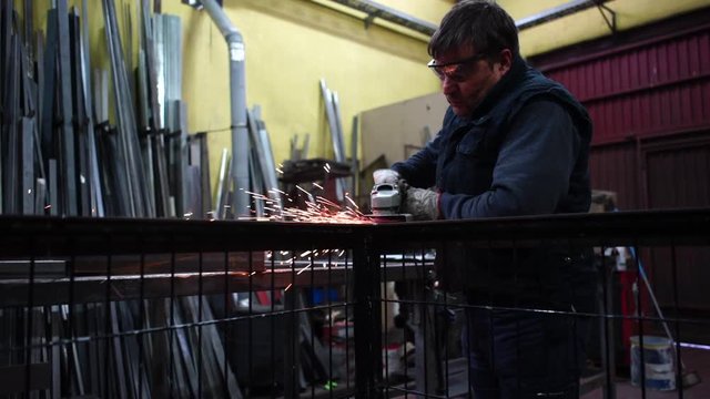 Man works with grinder cutting metal.