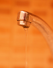 Water flowing from the tap in orange background, save water!
