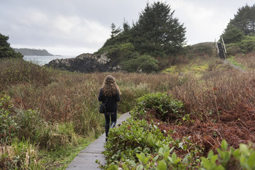 Girl walking on boardwalk at coast, Cox Bay, Pettinger Point, Pacific Rim National Park Reserve, Tofino, British Columbia, Canada