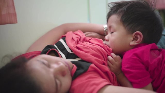 Asian boy about 2 year and 3 months sleeping while breastfeeding by his mother