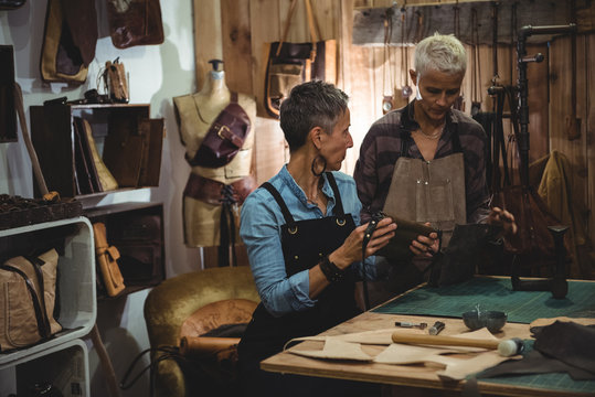 Craftswomen discussing over leather bag - Powered by Adobe