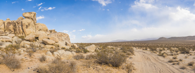 Un chemin de terre s& 39 enroule autour de tas de gros rochers dans le désert du sud de la Californie.