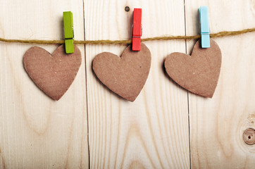 Handmade paper hearts hanging on clothesline over wood boards
