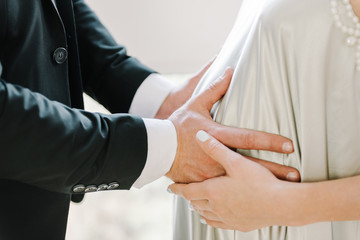 Obraz premium Male and female hands on pregnant belly