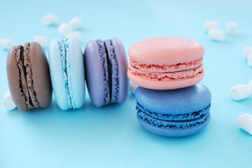 Colorful macaroons on a blue background with copy space. Raspberry, lavender, chocolate, blueberry, bilberry tastes with marshmallow