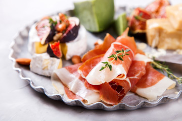 Cheese plate with thyme, a board. A different cheese with fresh figs Honey, walnut almonds and meat. Snack jamon, prosciutto, camembert, parmesan, brie green cheese with basil.selective focus.