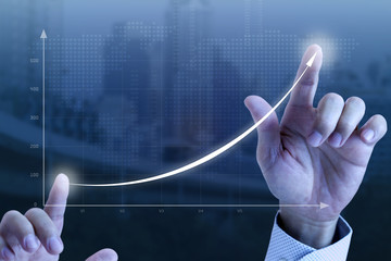 Close up of a businessman’s hands drawing an exponential line curve showing of business growth...