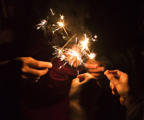 Group of happy people holding sparklers at party and smiling.