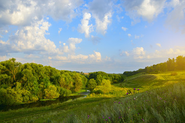 Obraz premium Sunny summer landscape with river at sunrise.Green hills with trees.