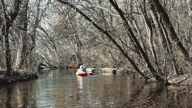 Senior woman is kayaking on the lake on a spring day. Woman boating on small river.