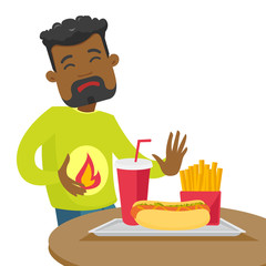 African-american man standing near table with fast food and having stomach ache from heartburn. Man suffering from a heartburn after fast food. Vector cartoon illustration isolated on white background