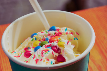 joghurt ice cream with sweet toppings like multicolored sprinkles 