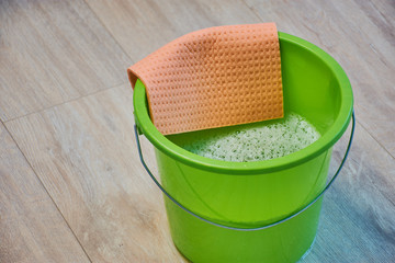 green bucket with cleaning water and a sponge cloth