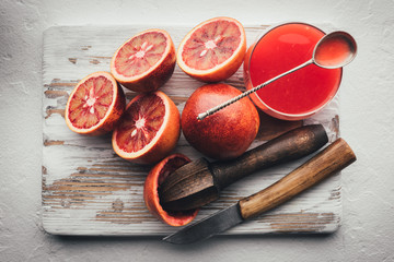 Red sicilian orange pieces and squeezer on wooden board closeup. Healthy diet vitamin concept. Food photography