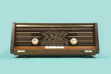 Antique retro radio seen from the front on a turquoise blue background