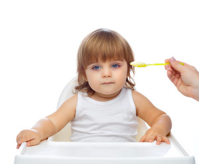 a handsome baby 1.6 years old sits in a white child's highchair. The concept of baby food. Food.