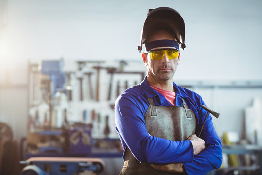 Portrait of male welder standing with arms crossed