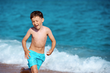 Caucasian boy at the seacost. He is running along the seaside wth his eyes beeing closed.
