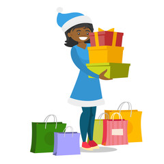 African-american woman in santa hat standing among shopping bags and holding gift boxes