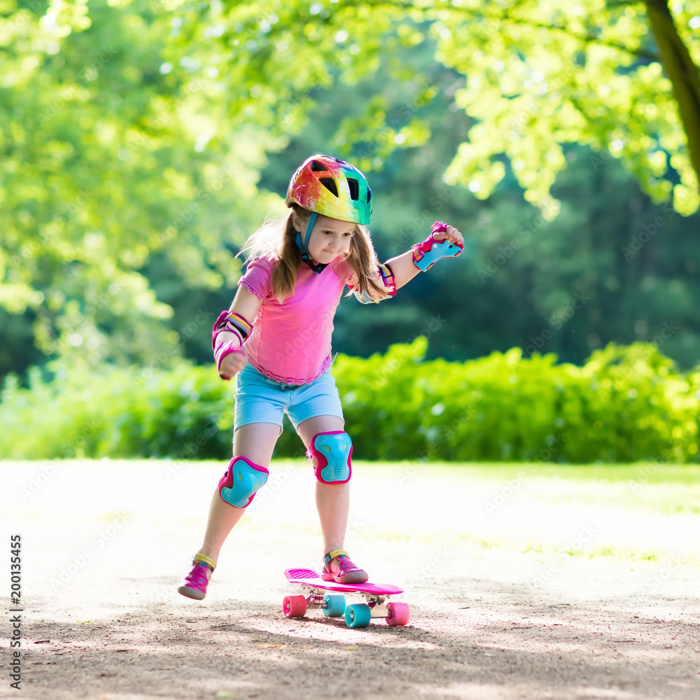 Wall mural Child riding skateboard in summer park