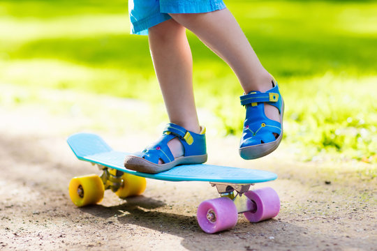 Child riding skateboard in summer park