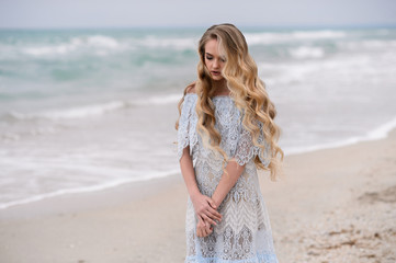 Beautiful girl in amazing dress walks on the beach