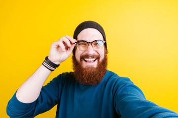 Happy bearded man touching eye glasses