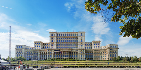 The Palace of Parliament is seen through the autumn foliage of trees and Liberty Avenue, central part of Bucharest, Romania