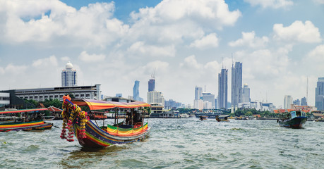 Tourist popular boat travel on the Chao Phraya river. To stay in downtown Bangkok. King Rama I Memorial Bridge and skyscrapers of Chinatown is seen on the horizon - obrazy, fototapety, plakaty