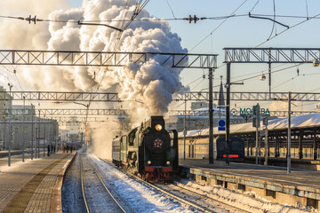 old black steam locomotive in Russia in the winter on the background of the Moscow railway station